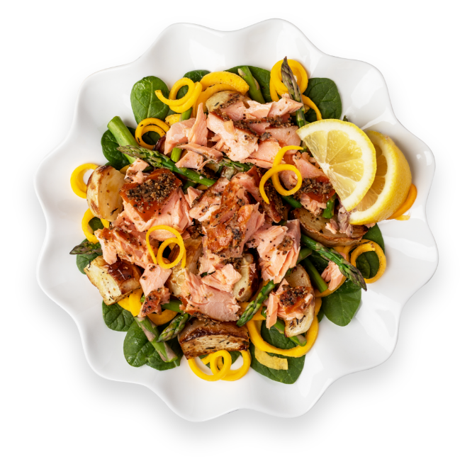 Salmon pasta spinach dish in a white serving plate with lemons